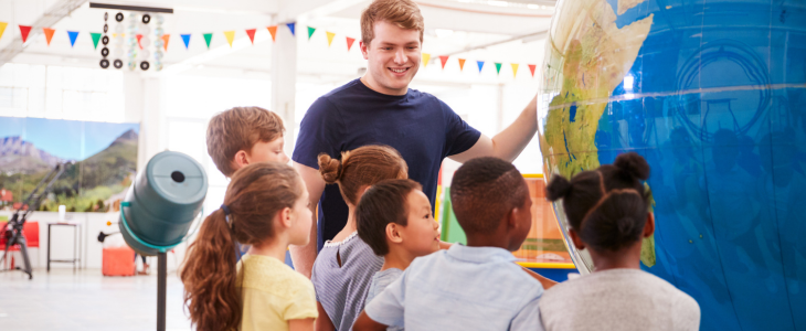 Students listen attentively while an instructor explains a globe